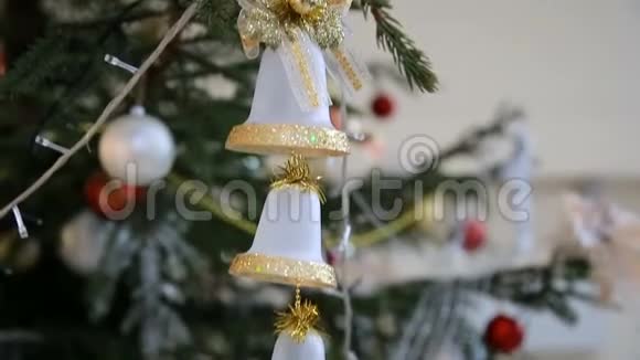圣诞树上挂着金色的铃铛挂在闪烁的彩色花环和特写中视频的预览图