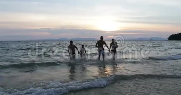 一群快乐的人手挽手从海上奔跑在夕阳下的沙滩上快乐的朋友视频的预览图