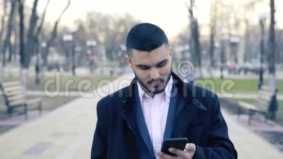 年轻英俊的商人站在街上用他的智能手机视频的预览图