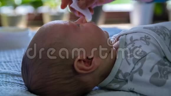 双手用棉花擦拭婴儿的脸视频的预览图