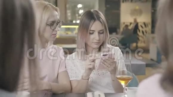 一群朋友在一家咖啡馆里在电话里展示照片然后大笑视频的预览图