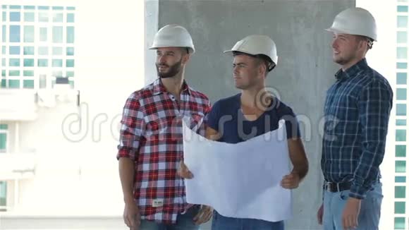 三个建筑工人在正在建造的大楼里摆姿势视频的预览图