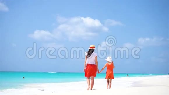 在热带海滩上可爱的小女孩和年轻的母亲两个家庭在暑假里玩得很开心视频的预览图