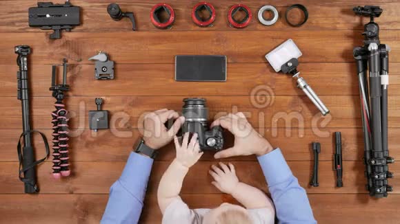 摄影师父亲和一个小儿子在拍摄前检查了相机木桌顶景幼儿触摸视频的预览图