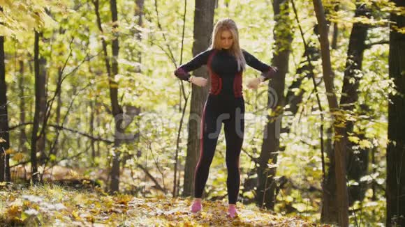 女人在户外做健身运动在秋天的森林里女人伸肘户外运动的苗条女孩视频的预览图