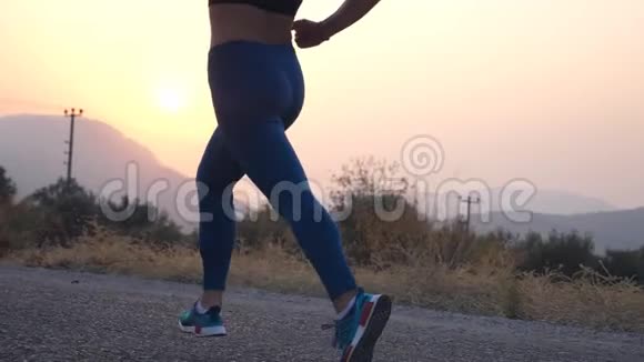 跟着年轻女孩在乡间小路上奔跑的脚女腿在大自然中慢跑活跃的生活方式慢动作视频的预览图