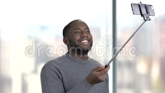 微笑的男人用自拍棒在模糊的背景上视频的预览图