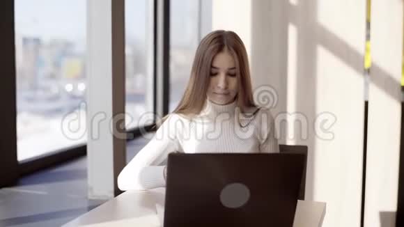 一个年轻的自由职业者女孩正坐在咖啡馆里用笔记本电脑远程工作视频的预览图