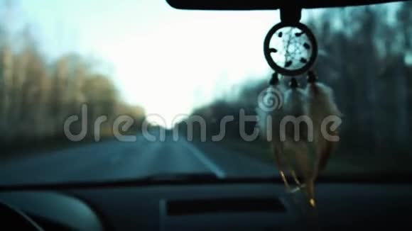 从车内后视镜上悬挂的捕梦器的视图开车旅行路和雪山的景色视频的预览图
