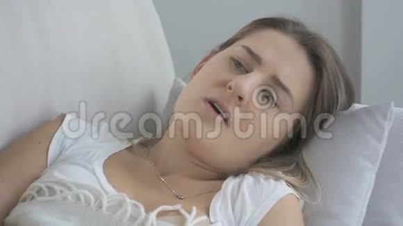 年轻生病的女人躺在客厅里咳嗽4K拍摄的录像视频的预览图