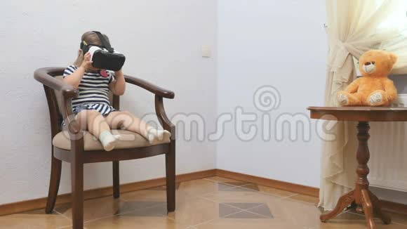 小女孩用虚拟现实眼镜坐在椅子上视频的预览图