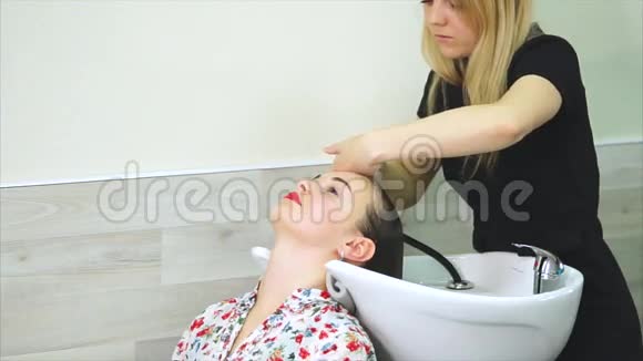 发廊女顾客在美容院用洗发水洗头视频的预览图