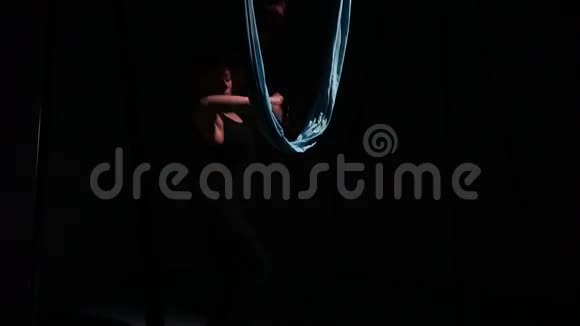 教练用空中瑜伽在吊床前黑暗中跳舞视频的预览图