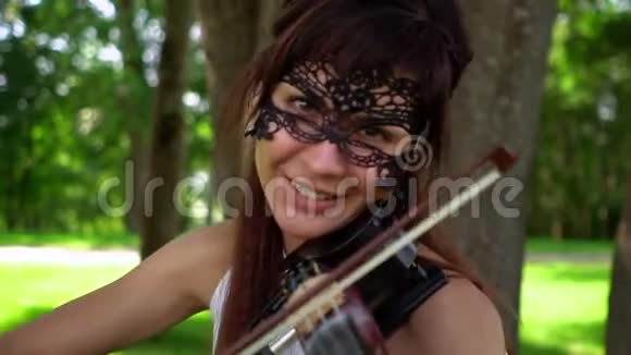 美丽的年轻女孩在美丽的公园里拉电小提琴视频的预览图