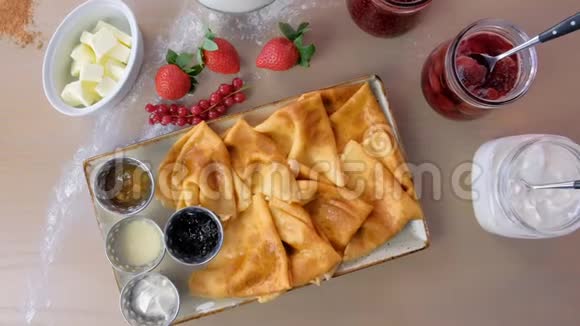 俄罗斯传统煎饼布里尼提供果酱酸奶油和草莓盘特写俯视图视频的预览图