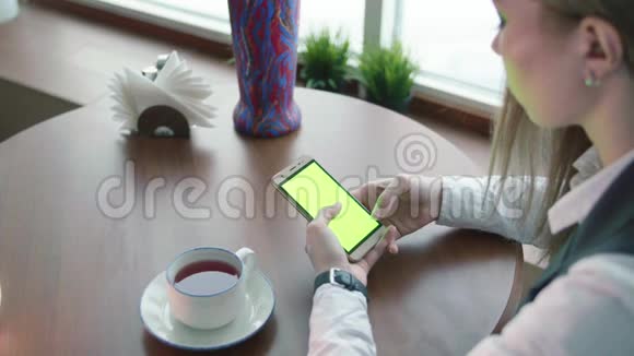 一位年轻的女巴士在咖啡馆工作她用绿色的屏幕打电话视频的预览图