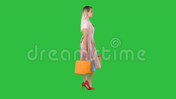 快乐的漂亮女孩拿着购物袋走在绿色屏幕上Chroma键视频的预览图