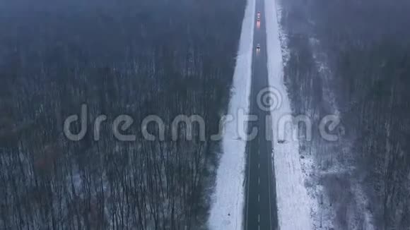 恶劣天气下通过冬季森林的道路交通鸟瞰图视频的预览图