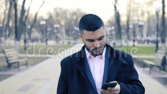 年轻英俊的商人站在街上用他的智能手机视频的预览图