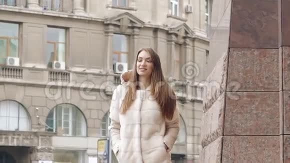 时髦的女人穿着毛茸茸的外套走着跑道在街上微笑慢慢地视频的预览图