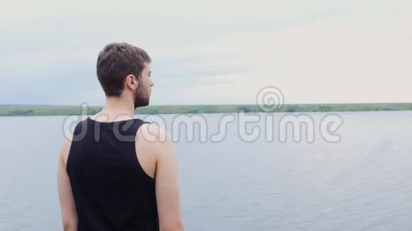 那个年轻人正向远处望着一个湖和一座山年轻人望着远处的湖视频的预览图
