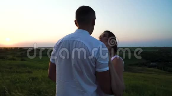 浪漫的年轻快乐的怀孕夫妇在夕阳下拥抱大自然视频的预览图