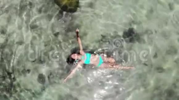 在热带岛屿令人惊叹的清澈水域中漂浮的女性的空中景色1920x1080视频的预览图