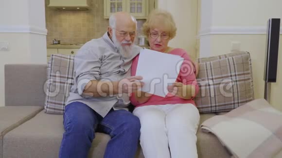 一对老夫妇一起在家看房租账单视频的预览图