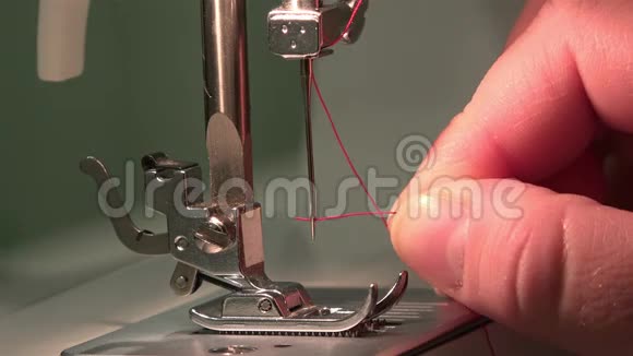 女用手在缝纫机的针上放一根红色的丝线视频的预览图