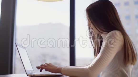 一个年轻的自由职业者女孩正坐在咖啡馆里用笔记本电脑远程工作视频的预览图
