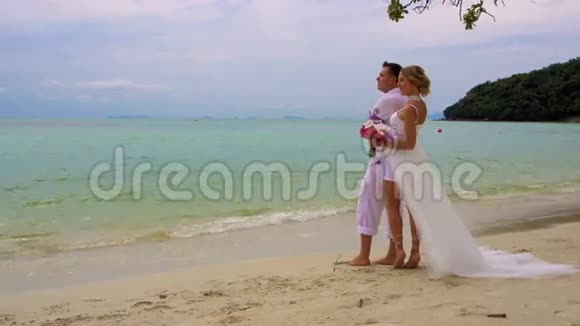 新娘和新郎站在海滩上新婚夫妇视频的预览图