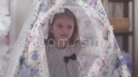 头上戴蝴蝶结的女孩藏在帐篷里视频的预览图