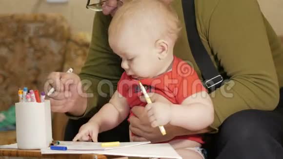 可爱的宝宝和他的祖父在纸上画着记号这孩子过敏眼睛发红孩子一年视频的预览图