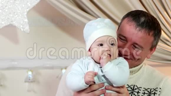 父亲和儿子一个父母和婴儿在冬天的家里玩耍一个幸福的家庭一个好爸爸把一个小孩子放在他的家里视频的预览图