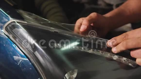 近距离拍摄一个人的手谁切乙烯基膜在一辆蓝色的汽车视频的预览图