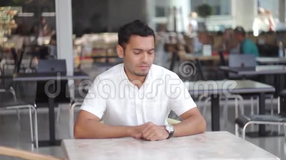 一个戴眼镜的年轻商人看着手表等待客户视频的预览图