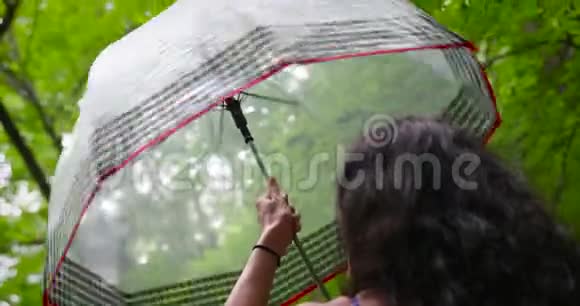 迷人的美女在雨天在美丽的公园扭伞视频的预览图