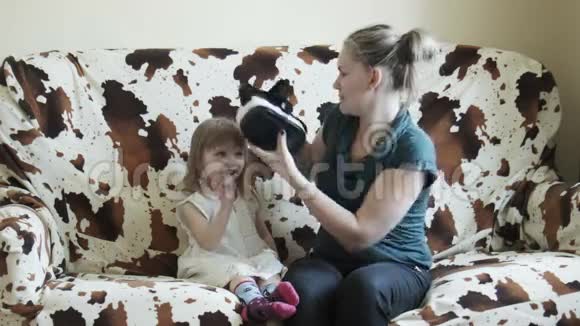 沙发上戴着VR护目镜的女孩和母亲视频的预览图