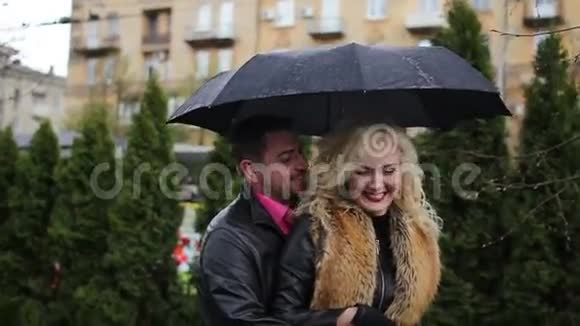 下雨时一对微笑的夫妇在黑伞下调情视频的预览图