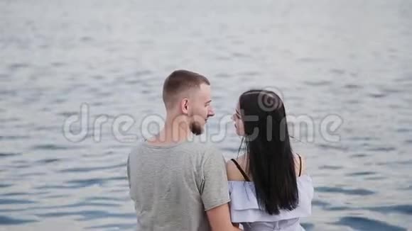 一对相爱的夫妇坐在河边亲吻和拥抱视频的预览图