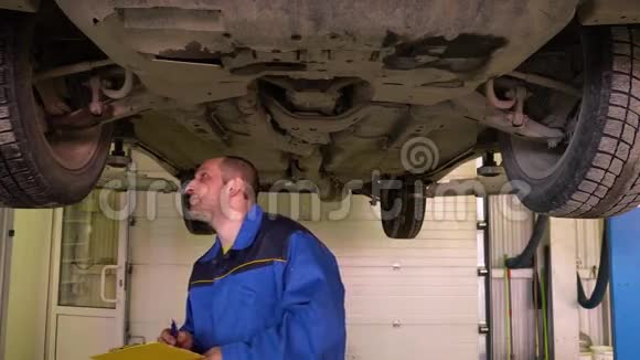 蓝色长袍的汽车修理工对车库内的运行进行诊断视频的预览图