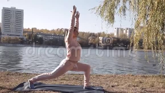 在公园里做瑜伽的女孩在河边视频的预览图