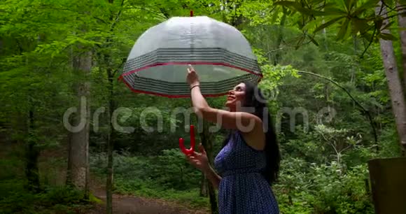 迷人的美女在雨天在美丽的公园扭伞视频的预览图