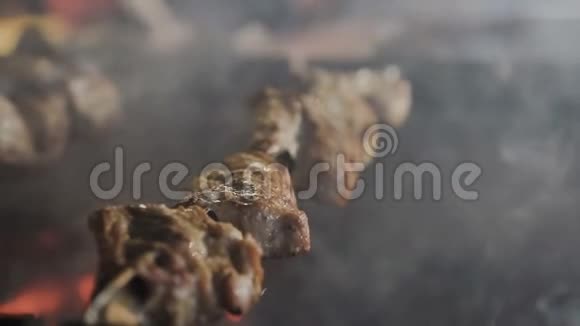用大量的烟雾烹饪烤肉烧烤金属扦子上的烤串视频的预览图