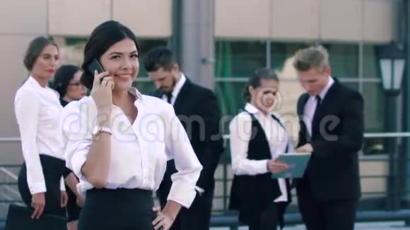 微笑的商务女性和她的同事在后台打电话积极聊天视频的预览图