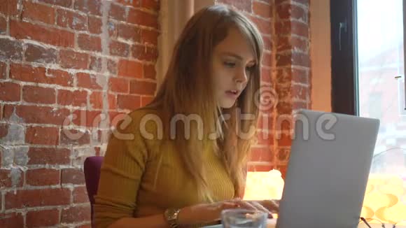 漂亮的女学生带着可爱的微笑在上网本上键盘一些东西漂亮的快乐女人在笔记本电脑上工作视频的预览图