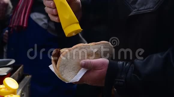男士特写将蛋黄酱芥末酱放在香肠的面包上视频的预览图