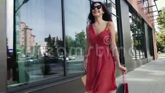 可爱的年轻女子带着购物袋走在商店橱窗前视频的预览图