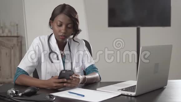 黑人女医生坐在办公桌前看镜头非裔美国人护士在柜子里的笔记本电脑上工作现代视频的预览图