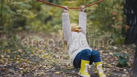 穿黄色靴子的小女孩在秋天公园的操场上玩绳子视频的预览图
